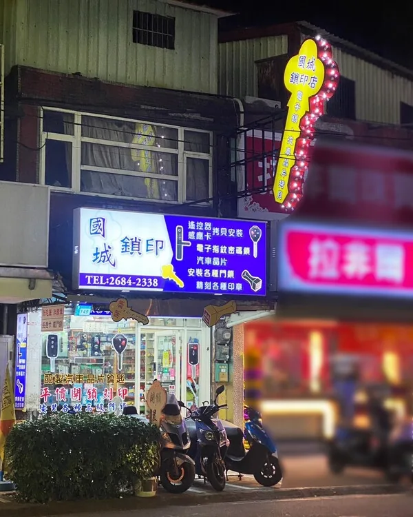 夜間點燈的國城鎖匙刻印店面,招牌與鑰匙造型霓虹燈亮著